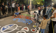 Indian Hindu Bengali youths, along with children, paint designs on the road during celebra...