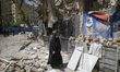 A veiled Iranian woman walks in front of her destroyed small supermarket in the Shahid Bor...