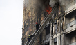 Firefighters climb a ladder as flames engulf a residential building near QSUT in Tirana, A...