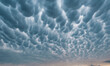 Mammatus clouds fill the evening sky over a rural farm landscape as severe storms move acr...