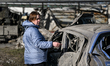 A woman stands by a car destroyed in a drone strike at a parking lot in Zaporizhzhia, Ukra...