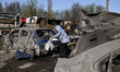A woman stands by a car destroyed in a drone strike at a parking lot in Zaporizhzhia, Ukra...