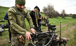 A soldier loads a machine gun mounted on a ground robotic complex during trials at a train...