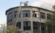 Firefighters use an aerial ladder platform to reach the roof of an academic institution da...