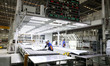 Workers cooperate with robots to produce automotive body sheet metal products in a mold st...