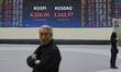 Investors react in front of an electronic scoreboard displaying the Korea Composite Stock...