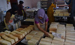 Workers remove ''Roti Sultan'' white bread from a mold at a home industry bakery in Malang...