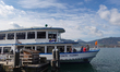 A passenger ferry with travelers is moored at a pier on Lake Tegernsee in Tegernsee, Upper...