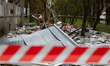 Debris lies on the ground behind barricade tape outside an apartment block in the Podilsky...