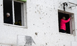 People stand in the windows of an apartment block in the Podilskyi district damaged by a R...