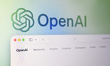 The OpenAI website homepage is displayed on a computer screen with the company's logo as a...