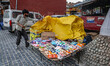A street vendor protects his belongings from strong winds in Srinagar, Jammu and Kashmir,...