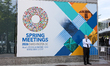 A man stands next to a sign at the 2026 Spring Meetings of the World Bank Group (WBG) and...