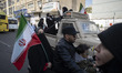 A family rides past a vehicle carrying armed women during a military parade of Iran's self...