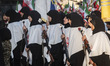 Pro-government supporters wearing shrouds carry AK-45 rifles as they participate in a mili...