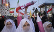 An Iranian schoolgirl holds up a model of an Iran-made ballistic missile while marching in...