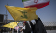 Veiled young Iranian women carry a national flag and a flag of Lebanon's Hezbollah while a...