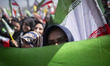 An Iranian demonstrator stands behind a national flag during a pro-government rally commem...