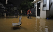 Residents wade through floodwaters inundating a residential neighborhood in Sawangan, West...