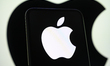 The Apple logo is displayed on a smartphone screen with another of the company's logos in...