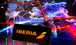 In this photo illustration Iberia logo is shown on a mobile phone against a world map and...