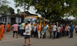 Voters stand in a queue at a polling station to cast their ballots during the first phase...