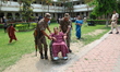 Security personnel assist a man with disabilities to cast his vote outside a polling stati...