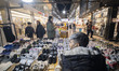 A sidewalk vendor sits behind his goods outside a shopping center in a business district i...
