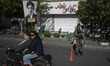 An Iranian police officer holding a rifle stands guard at a checkpoint in downtown Tehran,...