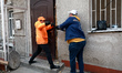 Men break open a door in a building damaged by a Russian military operation in the Khadzhy...