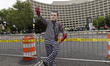 A protester wears a mask depicting United States Secretary of Defense Peter Hegseth as doz...