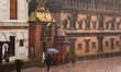 A visitor walks with umbrellas during heavy rain inside Bhaktapur Durbar Square premises i...