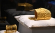 A ceremonial gold helmet and two gold bracelets are displayed during a media presentation...
