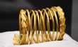 A ceremonial gold helmet and two gold bracelets are displayed during a media presentation...
