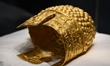 A ceremonial gold helmet and two gold bracelets are displayed during a media presentation...