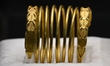 A ceremonial gold helmet and two gold bracelets are displayed during a media presentation...
