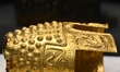 A ceremonial gold helmet and two gold bracelets are displayed during a media presentation...