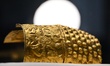 A ceremonial gold helmet and two gold bracelets are displayed during a media presentation...