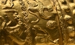 A ceremonial gold helmet and two gold bracelets are displayed during a media presentation...