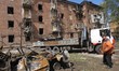 A municipal worker looks at a burnt-out car outside an apartment block in Dnipro, Ukraine,...