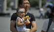 A child ride his farther to avoid summer heat as the temperature rises to 35℃ in Harbin,ca...