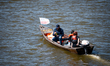 A small wooden motorboat carrying a ''Dzielnica Wisla'' flag moves along the Vistula River...