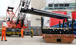 Workers prepare to load export coil steel onto a truck at the Dongfang Port Branch of Lian...