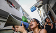 A young female protester shouts slogans through a megaphone as demonstrators raise market...