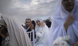 A couple displays their wedding rings during a mass wedding ceremony for Self-Sacrificing...