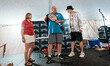 Dave Polster displays a championship belt while standing on stage next to a speaker in a s...
