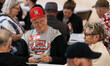 A man wearing a World Euchre Championship hat and shirt sits at a table during the 2026 Wo...