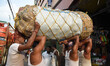 Labourers carry sacks of vegetables at a wholesale market of agricultural products in Kolk...