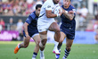 Joe Cokanasiga of Bath Rugby breaks a tackle by Louis Rees-Zammit of Bristol Bears during...