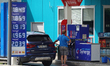 A man refuels his vehicle at an Esso gas station with fuel prices displayed in Herrsching...